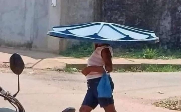 Pra ‘escapar’ do sol, mulher com tampa de caixa d’água na cabeça chama atenção no Acre