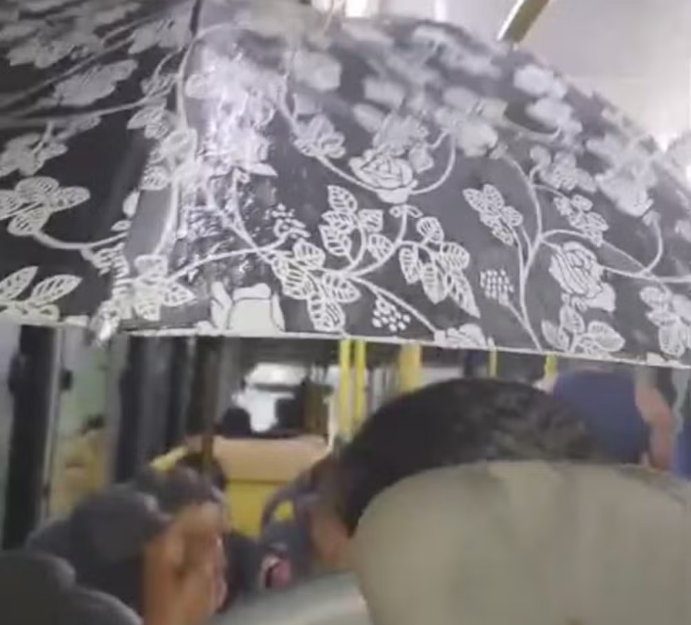 Com goteira em teto de ônibus, passageira usa guarda-chuva para se proteger em Rio Branco