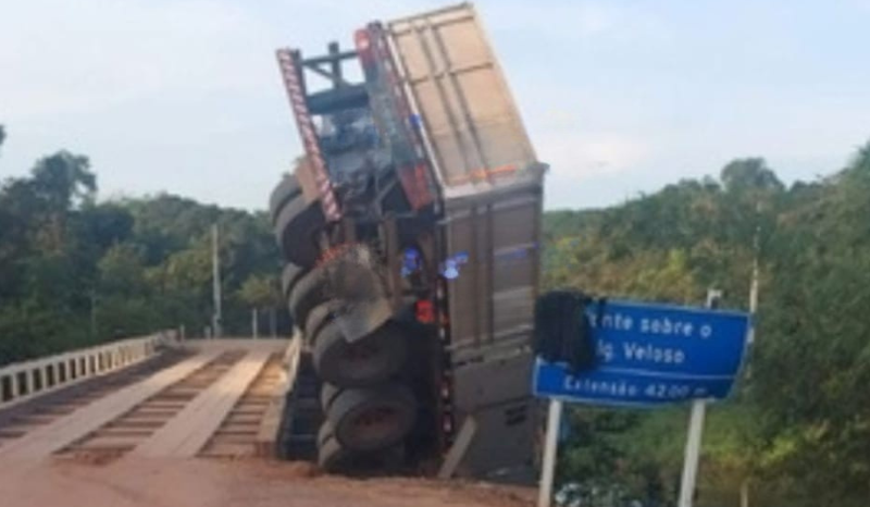 Carreta tomba e fica suspensa em ponte de madeira